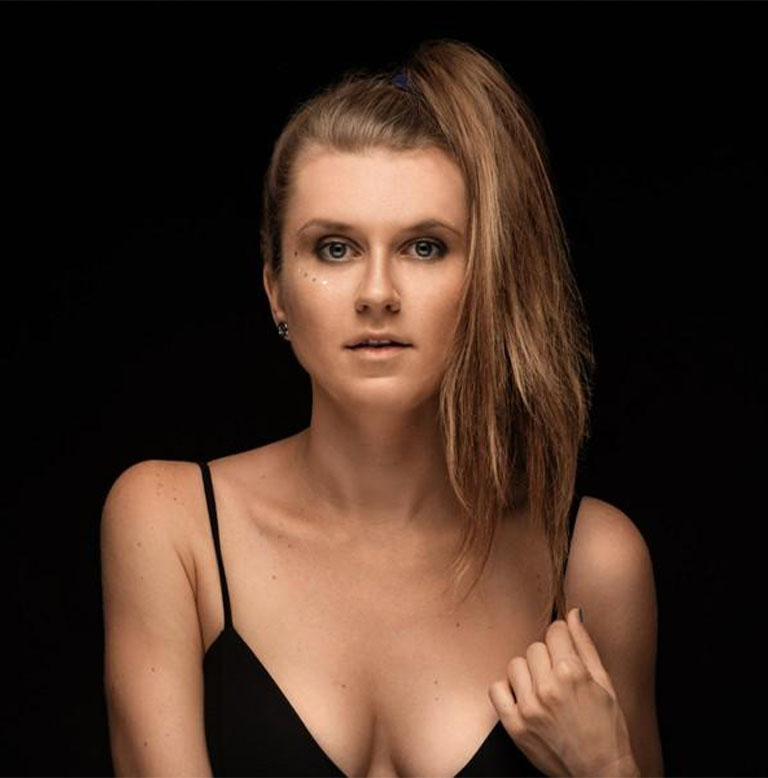 Porträt einer Frau mit langen, blonden Haaren, die in einem hohen Pferdeschwanz gebunden sind.