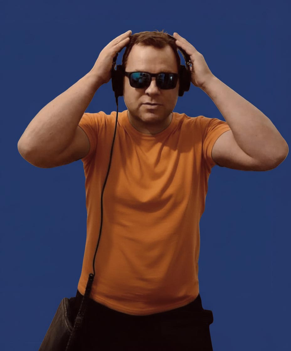 Mann trägt schwarze Sonnenbrille und Kopfhörer, während er in die Kamera schaut, bekleidet mit einem orangefarbenen T-Shirt.