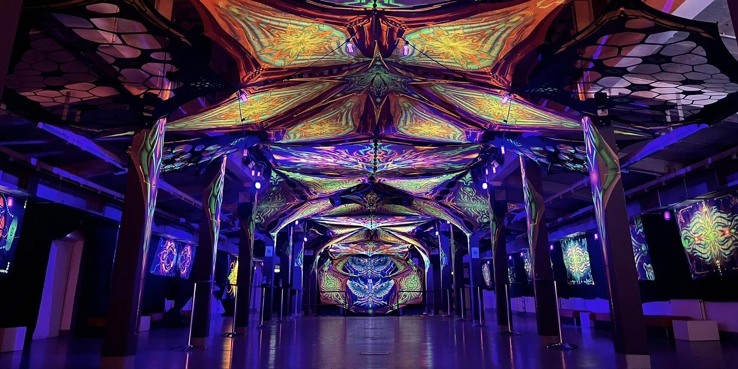 Bunte und leuchtende Indoordekoration mit geometrischen Mustern und Lichtern in einem Veranstaltungsraum.