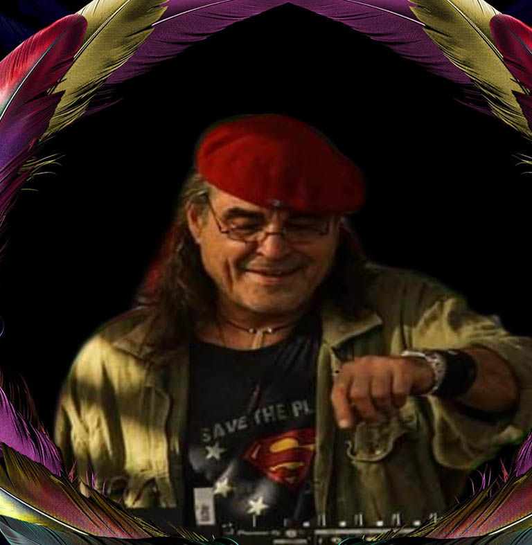 Mann mit rotem Hut und Superhelden-Shirt, der an einem DJ-Pult steht und Musik auflegt.